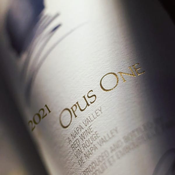 Close-up of a white wine bottle label with "2021 Opus One" in gold lettering.