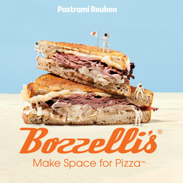 Bozzelli's Pastrami Reuben sandwich with tiny astronauts exploring it, against a blue and tan background.