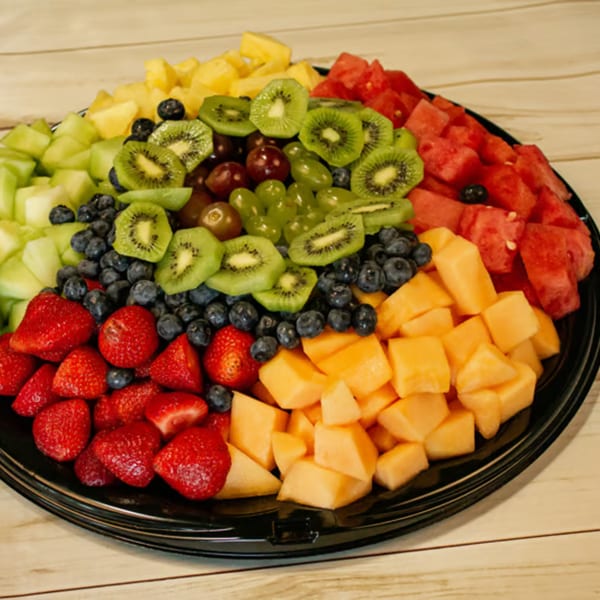 A colorful fruit platter with pineapple, honeydew, kiwi, grapes, blueberries, strawberries, cantaloupe, and watermelon.