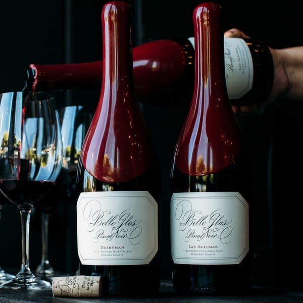 Two Belle Glos Pinot Noir bottles with a third pouring wine into a glass.