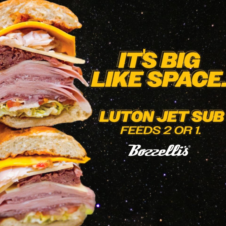 A large Bozzelli's sub sandwich, cut in half, against a starry space background.