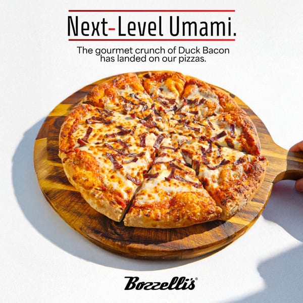 Bozzelli's duck bacon pizza, sliced and served on a wooden cutting board.