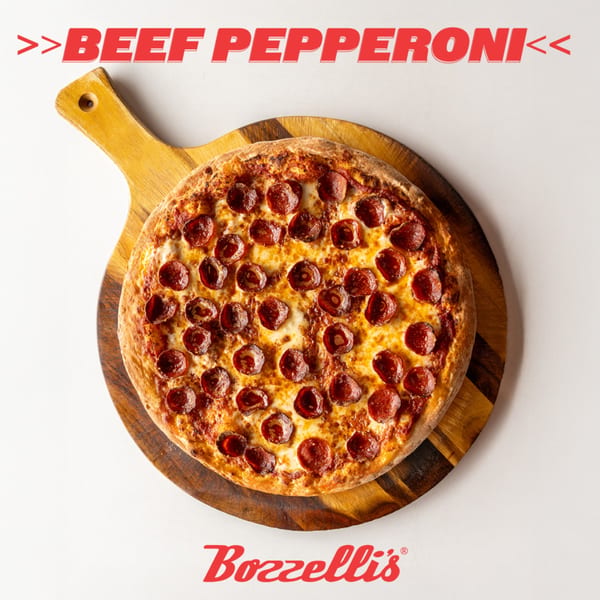 Bozzelli's beef pepperoni pizza, with melted cheese and crispy crust, on a wooden serving board.
