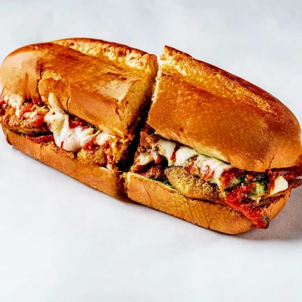 A Bozzelli's chicken parmesan sub, cut in half, with melted cheese and red sauce.